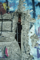 Germany Berlin, East German border guard looking through crack in the Wall in 1989.
