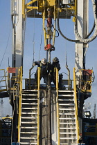 Canada, Alberta, Wabasca, Drilling rig floormen attaching drill pipe for an exploration well.