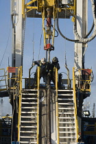 Canada, Alberta, Wabasca, Drilling rig floormen attaching drill pipe for an exploration well.