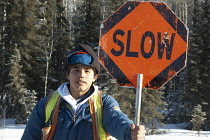 Canada, Alberta, Wabasca, Metis First Nation road flagger directing traffic related to oil and gas activities.