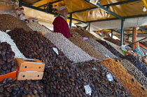Morocco, Marrakech, Djemaa el Fna square, Stall proprietor selling dried fruits and nuts.