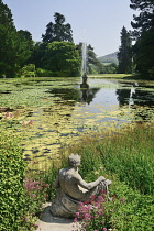 Ireland, County Wicklow, Enniskerry, Powerscourt House and Gardens, a statue by the Triton Lake with a fountain in the middle of the lake.