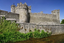 Ireland, County Tipperary, Cahir, Cahir Castle, General view of castle and surrounding wall with stream running past.