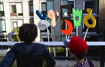 USA, New York, Manhattan, High Line linear park between buildings on a disused elevated railroad spur with people viewing a sculpture by Charlie Hewitt called Urban Rattle the first public art on the...