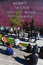 USA, New York, Manhattan, High Line linear park between buildings on a disused elevated railroad spur with people beside a wall painting by conceptual artist Ed Ruscha titled Honey I Twisted Through M...