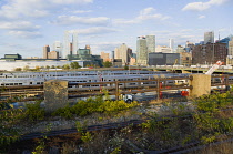 USA, New York, Manhattan, wild plant area and original rails of the disused elevated West Side Line railroad making the High Line linear park beside the Hudson Rail Yards with trains at the north end...