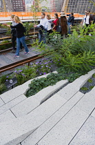USA, New York, Manhattan, people walking among plants and old rails on the High Line linear park on an elevated disused railroad spur called The West Side Line beside the Hudson Rail Yards.