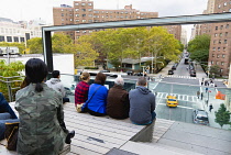 USA, New York, Manhattan, people seated at the 26th Street Viewing Spur on the High Line linear park on a disused elevated railroad watching traffic on the road below.