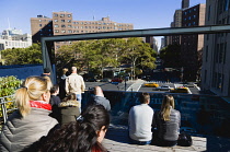 USA, New York, Manhattan, people seated at the 26th Street Viewing Spur on the High Line linear park on a disused elevated railroad watching traffic on the road below.