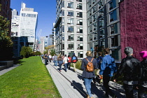 USA, New York, Manhattan, High Line linear park between buildings on a disused elevated railroad spur with people on a path beside the 23rd Street Lawn.