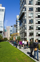 USA, New York, Manhattan, High Line linear park between buildings on a disused elevated railroad spur with people on a path beside the 23rd Street Lawn.