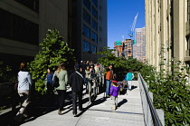 USA, New York, Manhattan, people walking on the Falcone Flyover on the High Line linear park between buildings on a disused elevated railroad spur of the West Side Line.