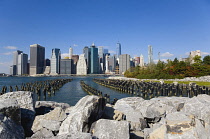 USA, New York, Lower Manhattan skyline skyscrapers seen from Brooklyn Bridge Park with wooden piles of Pier One in the East River.
