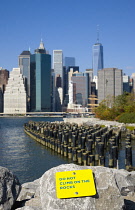 USA, New York, Lower Manhattan skyline skyscrapers seen from Brooklyn Bridge Park with wooden piles of Pier One in the East River.