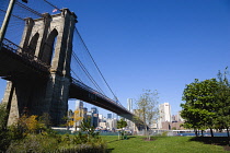 USA, New York, Brooklyn Bridge Park, The Empire Fulton Ferry section of the park below the supension bridge across the East River to the skyscraper skyline of Lower Manhattan.