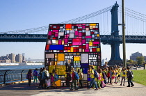 USA, New York, Brooklyn Bridge Park, schoolchildren at the colourful plexiglass house called Kolonihavehus by sculptor Tom Fruin below the Manhattan Bridge spanning the East River.