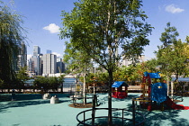 USA, New York, Brooklyn Bridge Park, deserted colourful children's playground by the Fulton Ferry Landing with the Lower Manhattan skyscraper skyline and East River beyond.