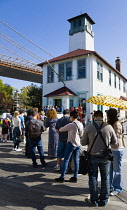 USA, New York, Brooklyn Bridge Park, queue of customers at The Brooklyn Ice Cream Factory in an old boathouse on the Fulton Ferry Pier below the suspension bridge.
