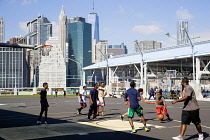 USA, New York, Brooklyn Bridge Park basketball courts on Pier 2 with Lower Manhattan skyscraper skyline beyond.