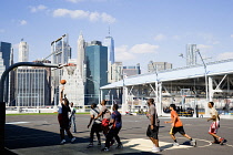 USA, New York, Brooklyn Bridge Park basketball courts on Pier 2 with Lower Manhattan skyscraper skyline beyond.