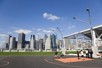 USA, New York, Brooklyn Bridge Park basketball courts on Pier 2 with Lower Manhattan skyscraper skyline beyond.