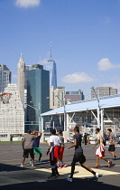 USA, New York, Brooklyn Bridge Park basketball courts on Pier 2 with Lower Manhattan skyscraper skyline beyond.