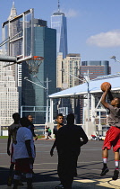 USA, New York, Brooklyn Bridge Park basketball courts on Pier 2 with Lower Manhattan skyscraper skyline beyond.