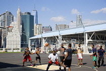 USA, New York, Brooklyn Bridge Park basketball courts on Pier 2 with Lower Manhattan skyscraper skyline beyond.