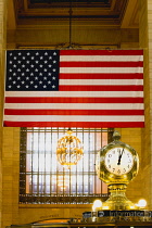 USA, New, York, Manhattan, The Central Information four sided clock in Grand Central Terminal main concourse with the Stars and Stripes flag hanging down from the ceiling behind.