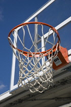 USA, New York, Brooklyn Bridge Park, empty basketball hoop and net against a blue sky on an outdoor court.