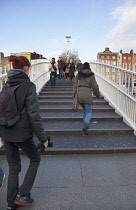 Ireland, Dublin, People crossing the Ha'penny Bridge across River Liffey viewed from the Temple Bar side.