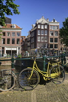 Netherlands, Noord Holland, Amsterdam, typical canal scene along the Herengracht with tall houses and a yellow bicycle by the railings.