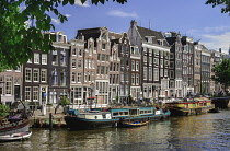 Netherlands, Noord Holland, Amsterdam, typical canal scene along the Herengracht with tall houses and houseboats by the sideawalk.