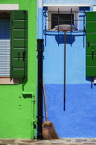 Italy, Veneto, Burano Island, Sweeping brushes at blue and green wall.