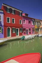Italy, Veneto, Burano Island, Colourful housing with red bopat in foreground on Fondamenta Pontinello Sinistra.