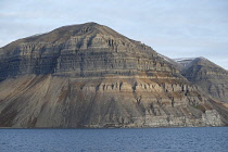 Norway, Svalbard Lateral rock strata, scree slopes, band of Gysum near the base at fjordside.