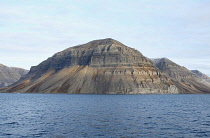 Norway, Svalbard Lateral rock strata, scree slopes, band of Gypsum near the base at fjordside.
