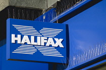 Business, Finance, Banking, Halifax sign on high street bank building with metal pigeon control spikes above it. **Editorial Use Only**