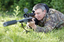 Sport, Gun, Shooting, Sniper wearing camoflage holding rifle with powerful scope and noise reduction muzzle.
