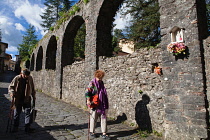 Italy, Tuscany, Lucca, Barga, Elderly pedestrians walking beside the Roman Aqueduct.