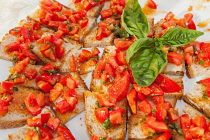 Italy, Tuscany, Lucca, Barga, Small slices of bread topped with tomato on display for a buffet.