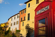 Italy, Tuscany, Lucca, Barga, British telephone box with facades of old town houses in the background.