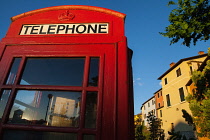 Italy, Tuscany, Lucca, Barga, British telephone box with facades of old town houses in the background.