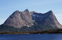 Norway, Nordland, Ballangen, Eidetinden Mountain  846 metres above sea level from the North by Eidfjorden.  Some patches of snow in sheltered areas and trees covering lower slopes.