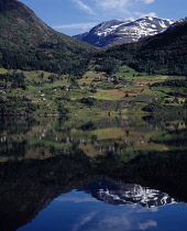 Norway, Sogn og Fjordane, Flo, View across Strynsvatn Lake reflecting agricultural landscape and village of Flo with Ringdalshornst mountain beyond.