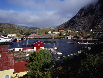 Norway, Lofoten, Moskenesoya Island, Reine fishing village.  Houses clustered around sheltered harbour with moored fishing boats.
