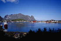 Norway, Lofoten, Moskenesoya Island, Sund fishing village.  Red and white painted houses overlooking small harbour with moored fishing boats.