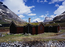 Norway, , More og Romsdal, Mountain refuge at the western end of Langfjelldalen off Trollstigveien with wooden walls and a turf roof.  Mountain landscape behind with snow lying in patches.