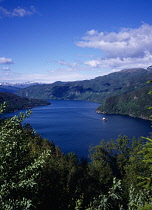 Norway, Rogaland, Saudafjorden, View north across fjord lined by tree covered landscape with small ship  Dyna Bulk.