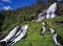 Norway, Rogaland, Svandalsfossen, Waterfall cascading over tiered rock face surrounded by trees and lush vegetation near town of Sauda.